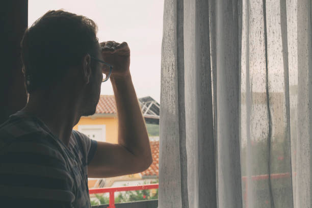 istock Silhouette of lonesome man looking through the window. 949850298