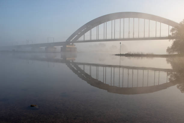 Bridge over the river Lek on a foggy morning Culemborg, the bridge over the river and its reflection in the water. lek river in the netherlands stock pictures, royalty-free photos & images