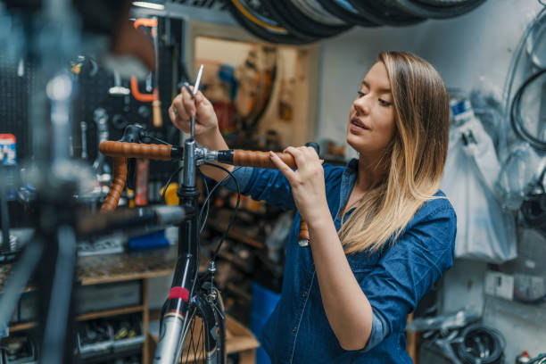Technician woman fixing bicycle in repair shop Woman bicycle mechanic is repairing a bike in the workshop. Technician woman fixing bicycle in repair shop. Young woman adjusting bike chain and repairing bicycle. Bike service. bike workshop stock pictures, royalty-free photos & images