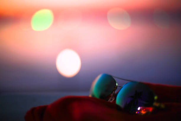 istock Summer poster with sunglasses, palms and bokeh effects. Blurred sunset beach background. 949861954