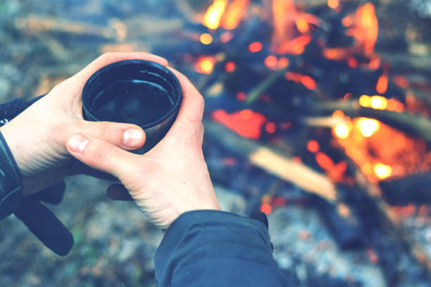 istock Man hands holding cup near the fire. Tomed 949862308
