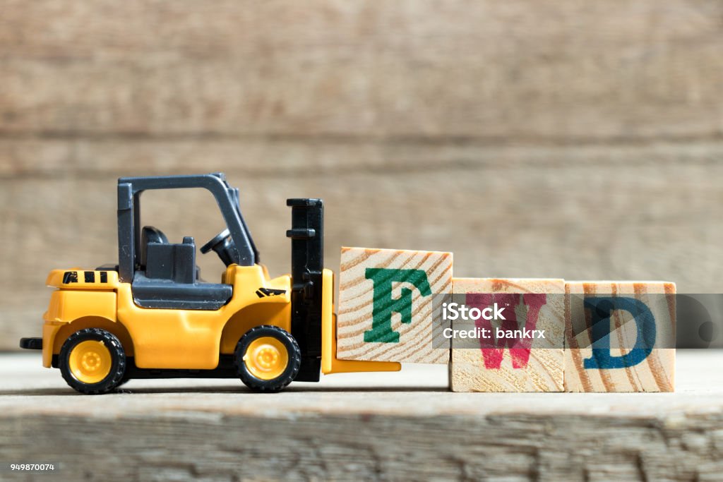 Toy yellow forklift hold letter block F to complete word FWD (Abbreviation of forward)on wood background Aspirations Stock Photo
