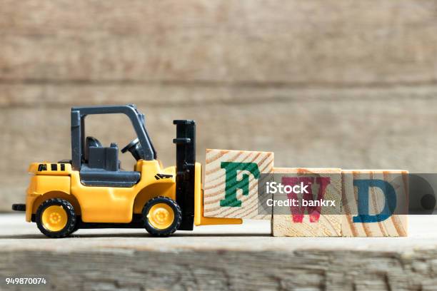 Toy Yellow Forklift Hold Letter Block F To Complete Word Fwd On Wood Background Stock Photo - Download Image Now