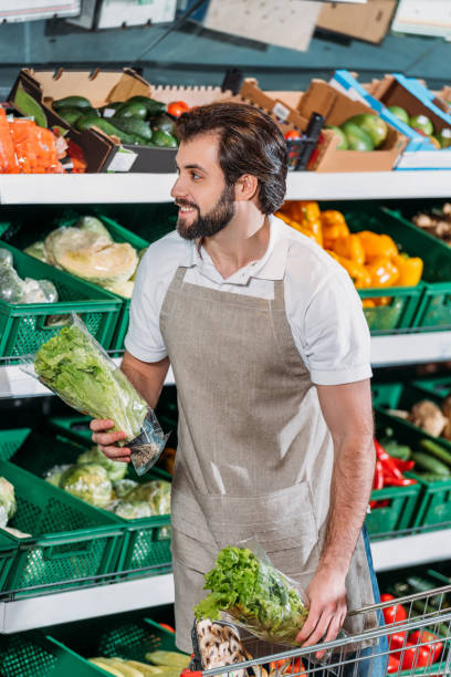 istock smiling shop assistant arranging fresh vegetables in grocery shop 949879912