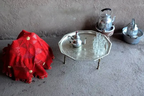 Requisites for a traditional Berber tea ceremony in Morocco: silver tray, teapot, kettle, glasses, stove, covered basket.