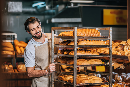 sonriente hombre dependienta arreglando pasteles frescos en supermercados photo