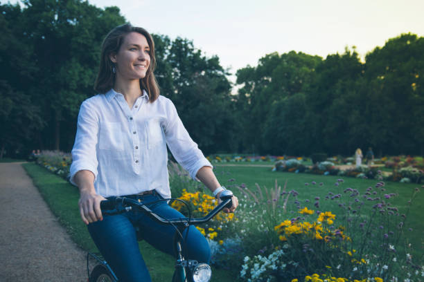 istock Young woman riding bicycle in park 949892664