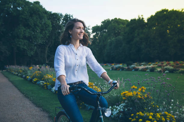istock Young woman riding bicycle in park 949892666