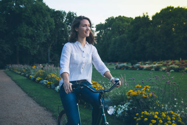 istock Young woman riding bicycle in park 949892670