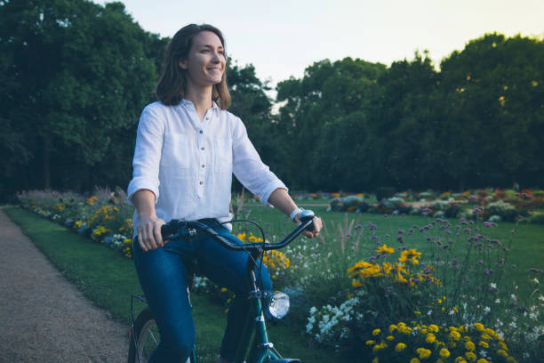 istock Young woman riding bicycle in park 949892744