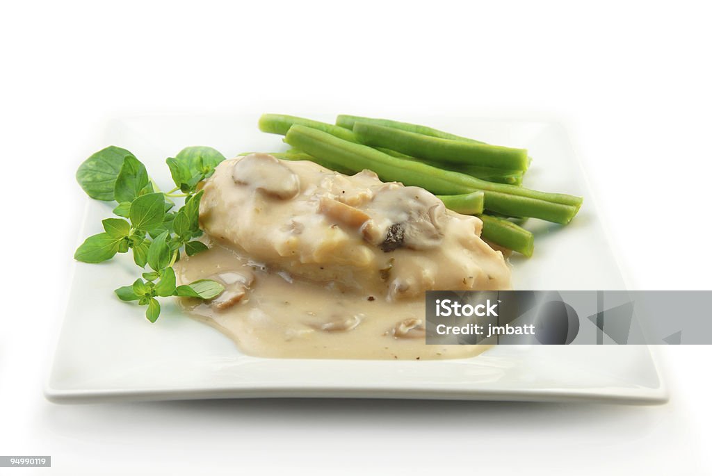 Chicken with cream and mushroom sauce with veggies Chicken breast in a cream mushroom sauce with steamed vegetables on a white background. Chicken Meat Stock Photo