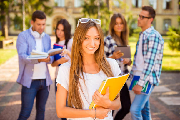 istock happy cute girl standing near university and holding notebook 949904342