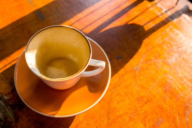 A side lit cup and saucer sit on a glass table, steam is visible rising from the cup.