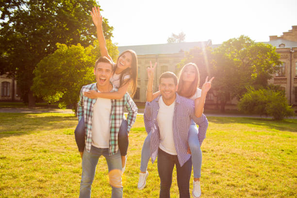 istock four lovers having fun. attractive  boyfriends piggybacking their girlfriends at weekend on grass 949918414