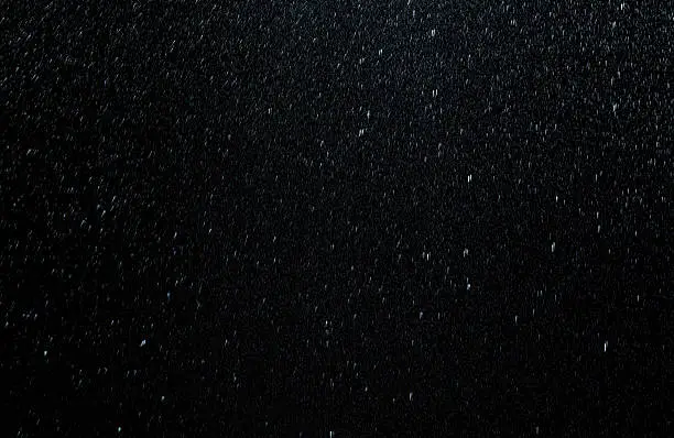 Photo of Raindrops falling down on black background