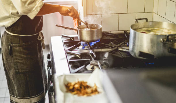 istock Male chef cooking in restaurant kitchen - Cook at work during dinner service - Italian style cuisine, lifestyle and healthy food concept - Focus on pot 949940840