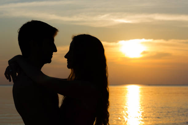 istock Man and woman hug at sunset on the ocean 949944832