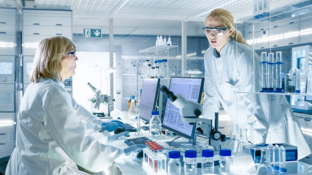 istock In Modern Laboratory Senior Female Scientist Discusses Work with Young Female Assistant. Laboratory Has Computers, Beakers and Other Technology for High Tech Scientific Analysis. 949947220