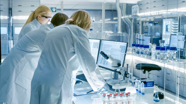 istock Back View of Team of Senior and Young Scientists Working on Problem Solution. They're Looking for Information on a Computer. Their Laboratory is Ultra Modern. 949947240