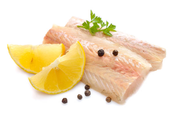Raw Hake fish fillet pieces with lemon. Isolated on white background.