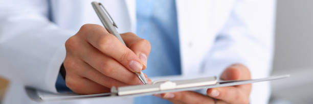 bras de la femme médecin tenez stylo argenté et la tablette pendant - document healthcare and medicine stethoscope history photos et images de collection
