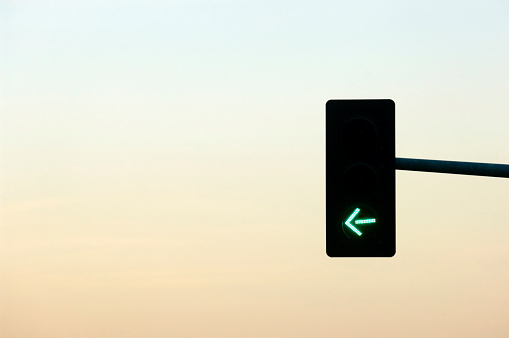 Streetlight at dusk with green left arrow