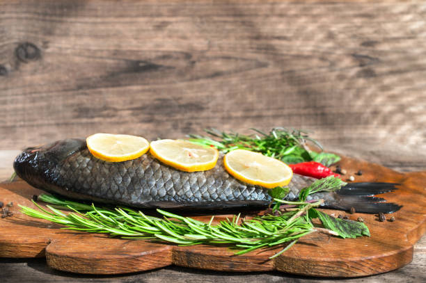 istock Fresh fish with herbs and lemon before cooking on wooden background 949967714