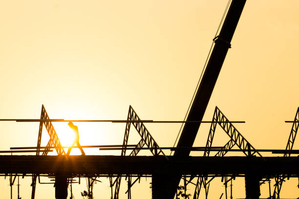 istock Silhouette engineer standing orders for construction crews to work on high ground heavy industry and safety concept over blurred natural background sunset pastel 949972300