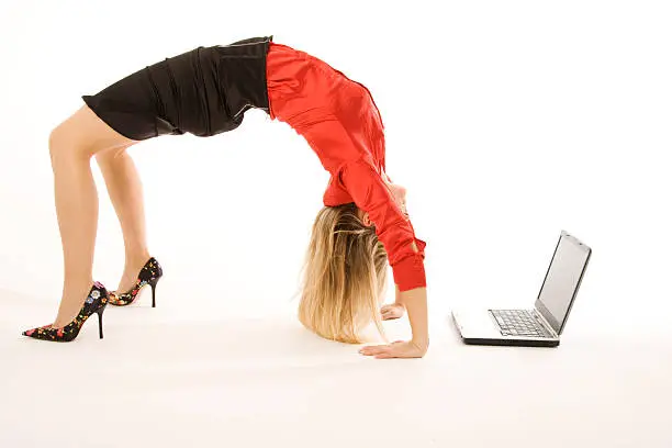 Photo of Business woman in heels doing back bend near laptop