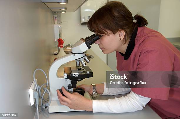 Joven Enfermera Espera A Través De Un Microscopio Foto de stock y más banco de imágenes de Microscopio - Microscopio, Adulto, Adulto joven