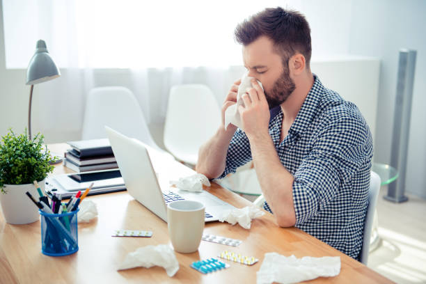 istock businessman having cold in the head and sitting at workplace 950027814
