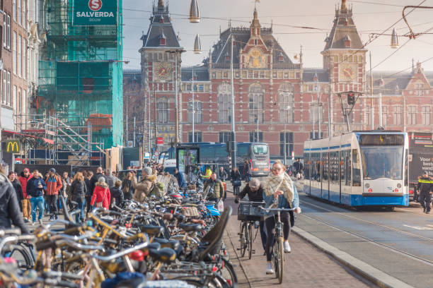 Amsterdam, The Netherlands - March 29, 2018: Tourists walking in front of the central station of Amsterdam near a tram