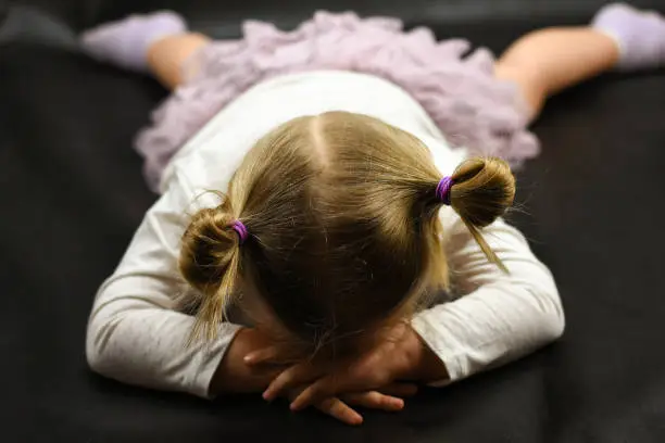 Photo of Child girl upset lying on the floor and crying on a black background