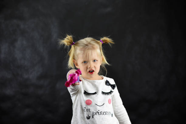 istock Child girl conjures a magic wand on a black background 950039098