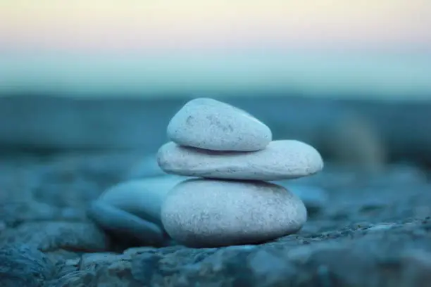 a pyramide of zen stones on the rocky beach during sunset