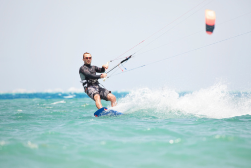 Young girl splashing in a water while windsurfing in a blue sea in a summertime.