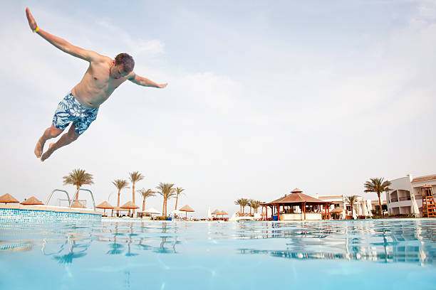 Man jumping in swimming pool stock photo