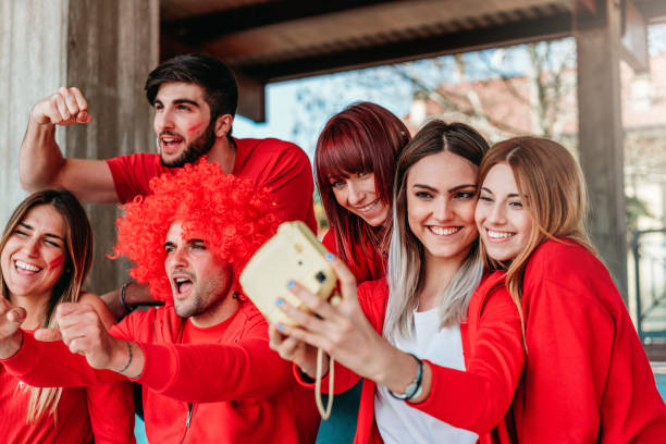 istock Fans at stadium together taking selfie with instant print camera 950062624