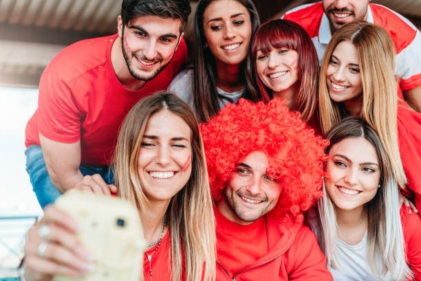 istock Fans at stadium together taking selfie with instant print camera 950062734
