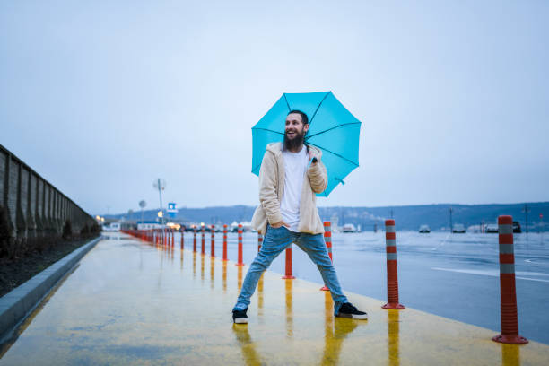 Urban Eastern European with hand in pocket. Holding an umbrella with legs apart, somewhere in Varna, Bulgaria.