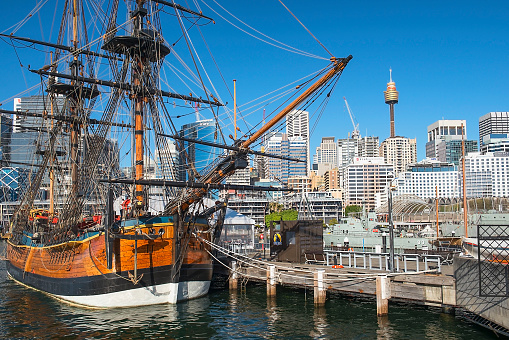 Sydney, Australia - March 11, 2018: replica of James Cook's HM Bark Endeavour, moored alongside the Australian National Maritime Museum in Darling Harbour with skyscrapers of CBD in the background