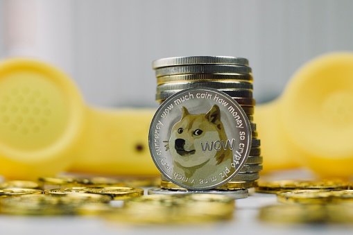 Digital currency physical metal dogecoin coin. Yellow phone communication concept.
