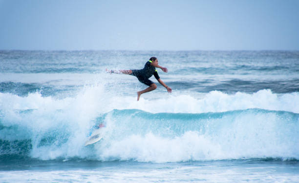 istock Man Jumping While Surfboarding In Sea Against Sky 950108704