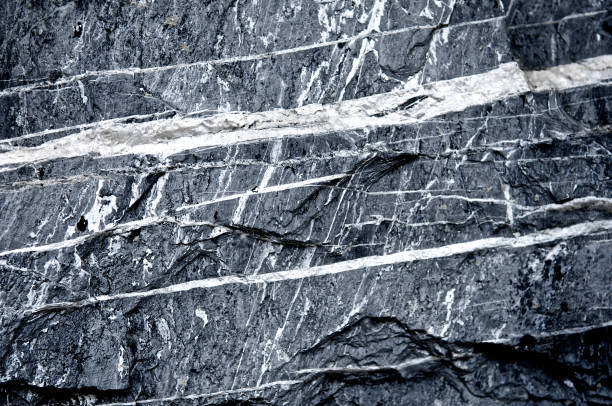 istock Granite stone scratched wall background grunge texture rough. Abstract construction concrete stone wall. Metamorphic rock. Cool and chic adventure wallpaper. Black and white color. Close up. 950111738