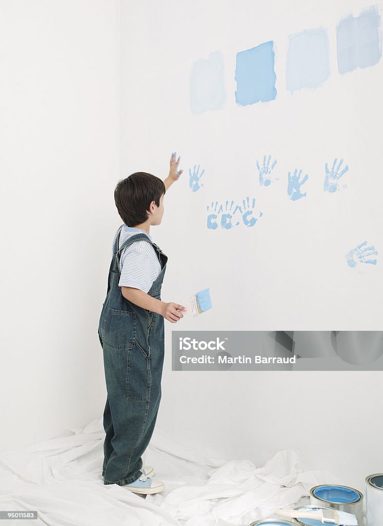 Garçon putting handprints avec de la peinture sur le mur - Photo de Mur libre de droits