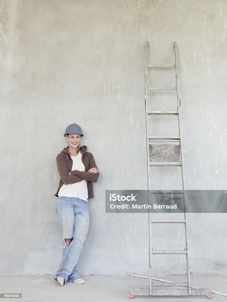 Femme portant Chapeau dur et s'appuyant sur un mur avec échelle - Photo de Cadrage en pied libre de droits