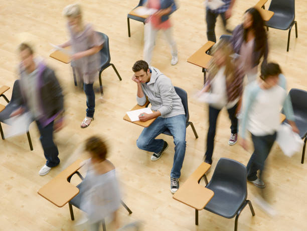 étudiants se déplacer autour de l'homme au bureau en salle de classe - struggle photos et images de collection