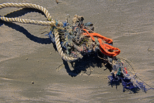 Old buoy and rope broken from the fishing net buried in the sand on the sea shore in Turkey. Environmental conservation.