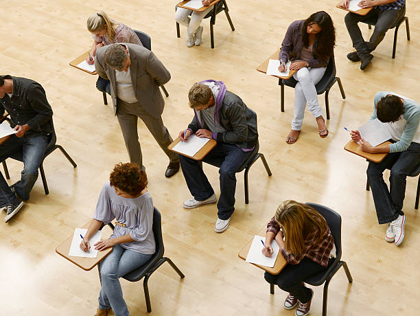 professeur marche par les étudiants de faire un test dans une salle de classe - exam photos et images de collection