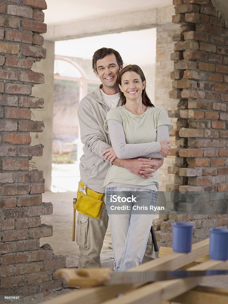 Coppia abbracciare nel porta di casa in costruzione - Foto stock royalty-free di Lavorare